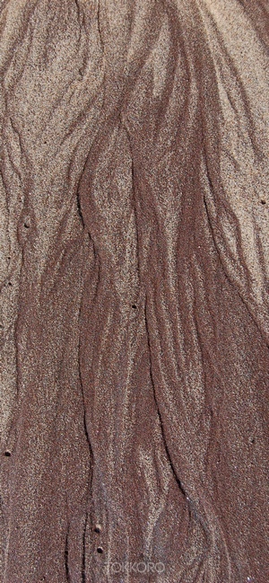 Close-up of wet sand with brown streaks