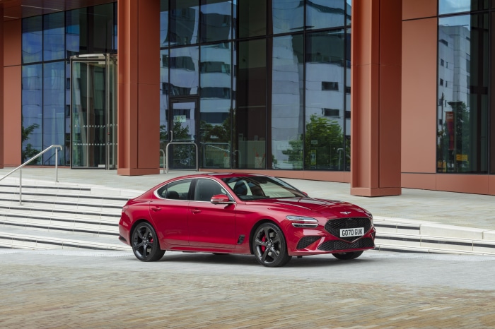Red Genesis G70 2.0T 4K parked in front of a modern building