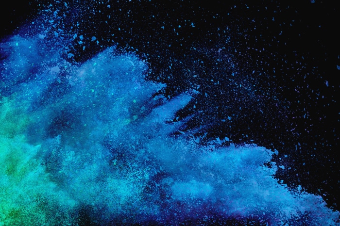 Blue and green powder explosion on black background