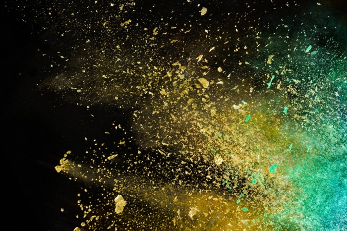 Explosion of yellow and green powder on black background
