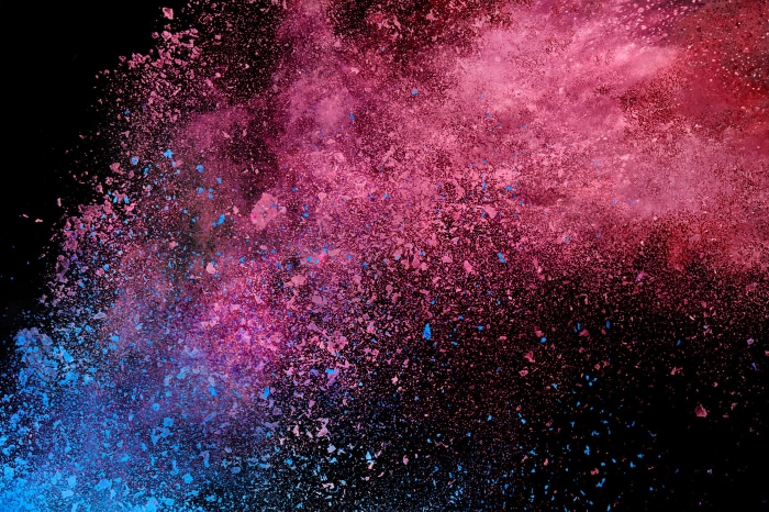 Explosion of pink and blue powder on black background