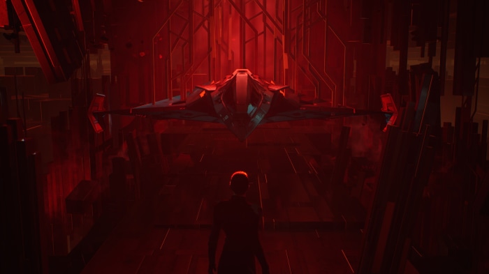 A person stands before a futuristic spaceship in a red chamber