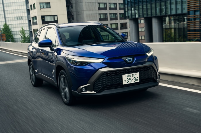 Blue Toyota Corolla Cross Hybrid SUV driving on a city road