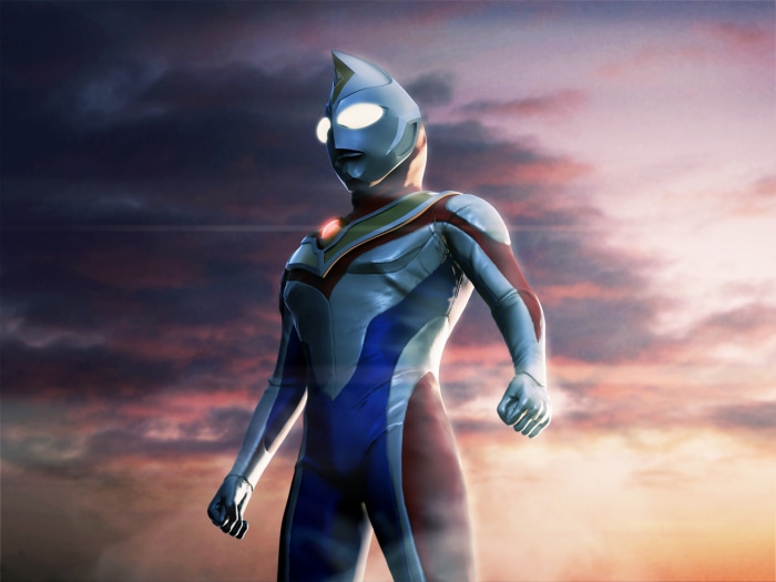 Ultraman Tiga standing against a sunset sky