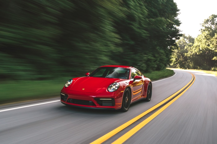 Red Porsche 911 Carrera GTS driving on a road