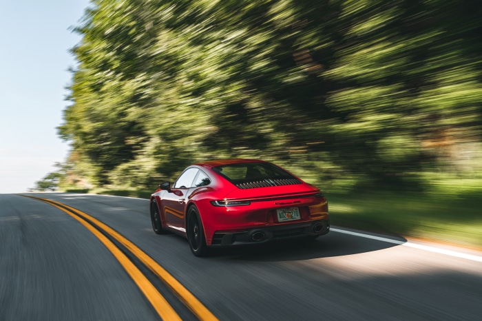 Red Porsche 911 Carrera GTS driving on a road