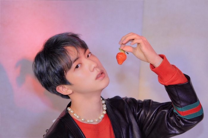 Jin from BTS holding a strawberry