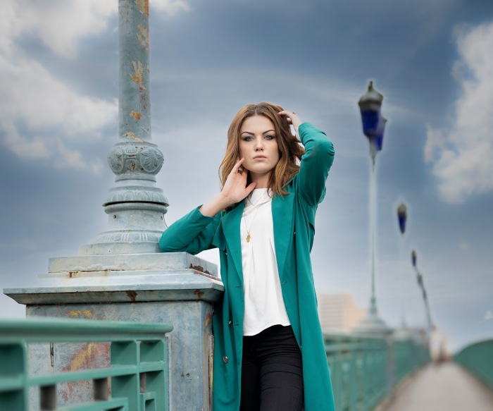 Woman in teal coat on bridge