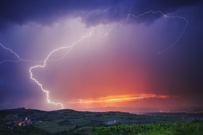 Lightning storm over vineyards and a castle at dusk