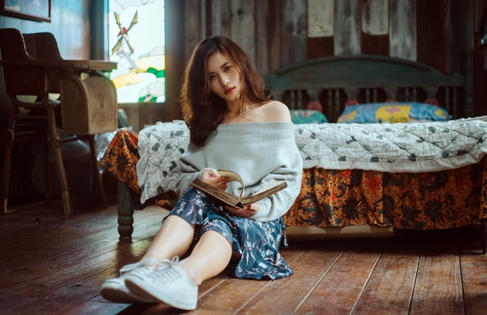Asian woman reading a book on the floor