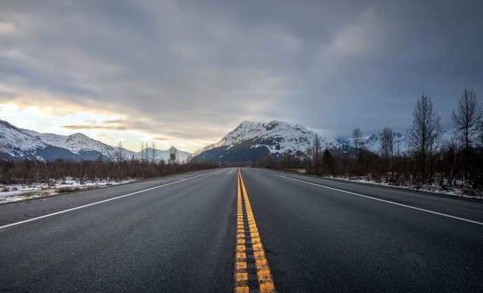 Road with snow-capped mountains and cloudy sky 4K