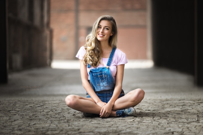 Young woman in denim overalls sitting outdoors