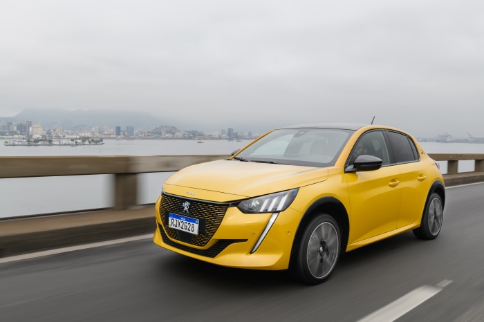 Yellow Peugeot E-208 GT driving on a bridge