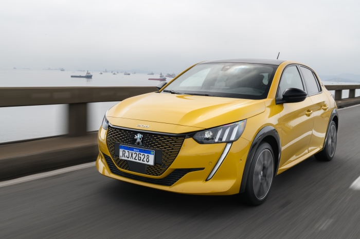 Yellow Peugeot E-208 GT electric car driving on a bridge