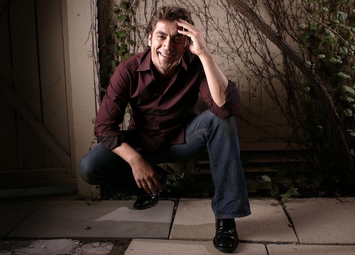 Javier Bardem crouching outdoors