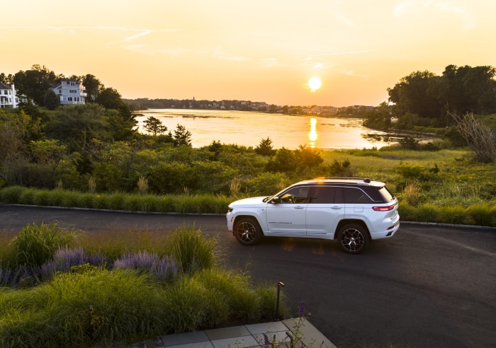 2022 Jeep Grand Cherokee Summit Reserve 4xe driving by a lake at sunset