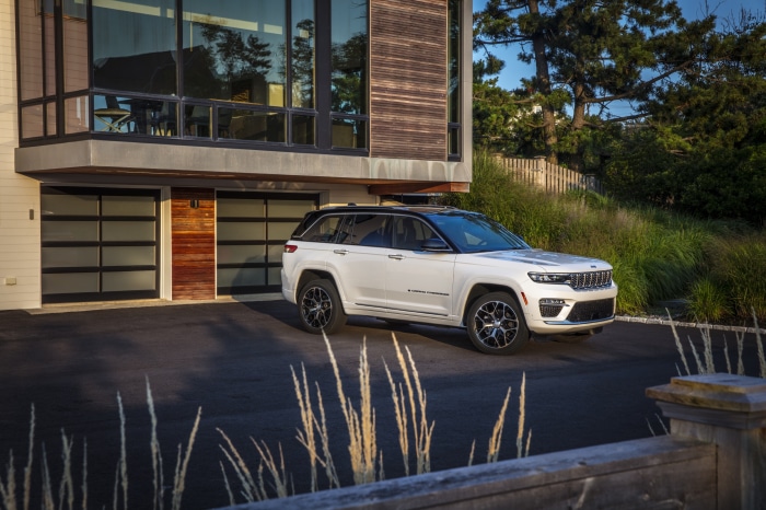 White Jeep Grand Cherokee Summit Reserve 4xe parked in front of modern house