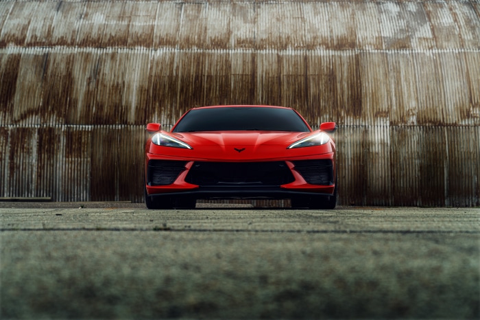 Red Corvette C8 parked in front of a corrugated metal wall