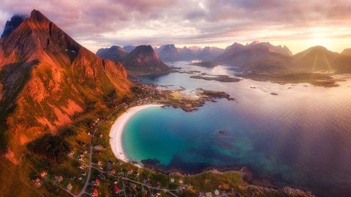 Aerial view of a coastal village and mountains at sunset