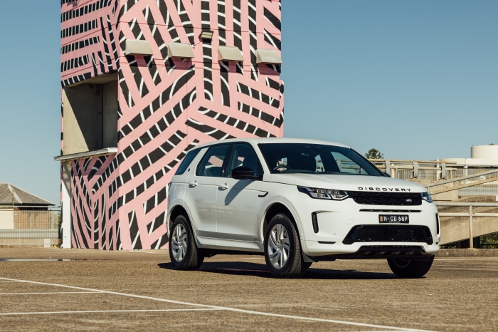 White Land Rover Discovery Sport parked near a building with pink and black pattern