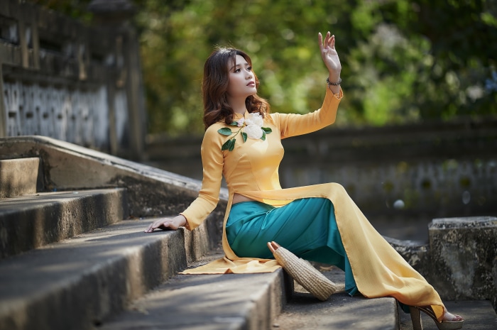 Asian woman in traditional dress sitting on stairs