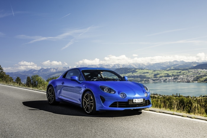 Blue Renault Alpine car on a road with mountains and lake