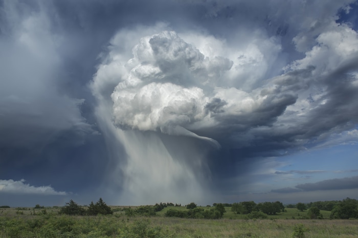 Storm clouds with rain over a grassy field