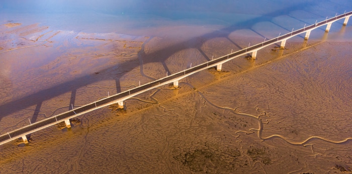 Aerial view of a long bridge over a mudflat