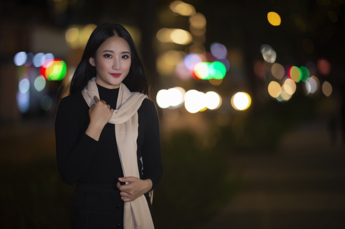 Asian woman with scarf at night with bokeh lights