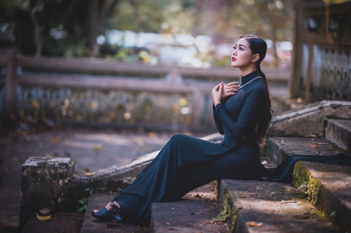Asian woman in black dress sitting on stairs