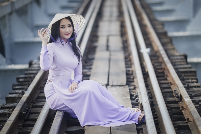 Asian woman in conical hat on train tracks
