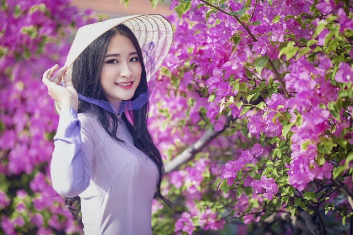 Asian woman in conical hat with pink flowers
