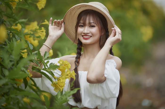 Asian woman with braids and hat in yellow flowers
