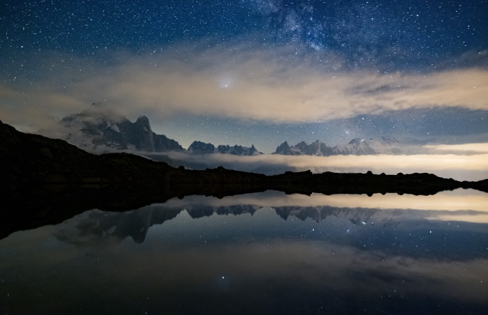 Mountain range reflection under starry sky
