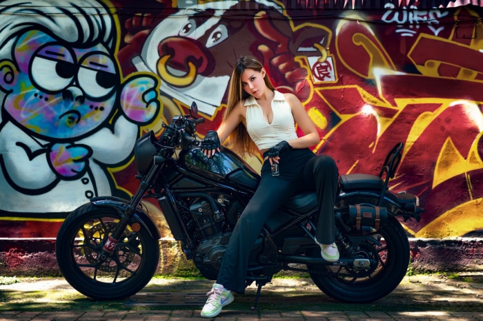 Woman on a motorcycle in front of graffiti