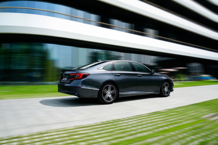 Honda Accord Sport Hybrid driving past modern building