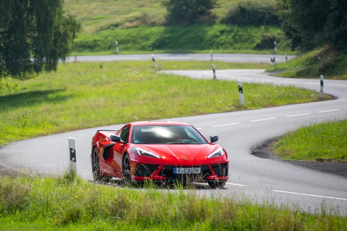 Red Chevrolet Corvette Stingray driving on a winding road
