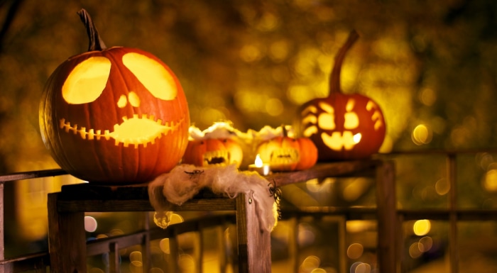 Carved Jack-o'-lanterns on a railing at night