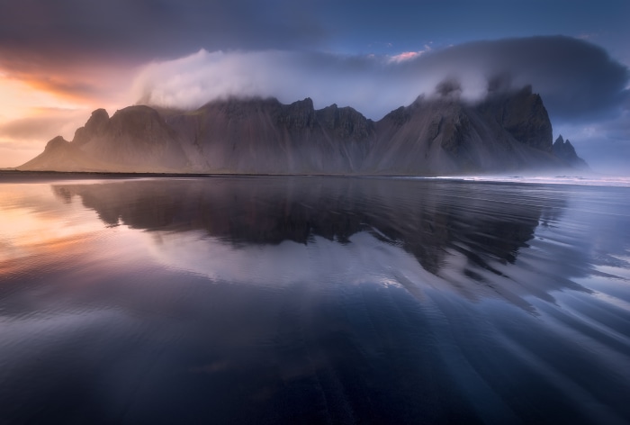 Vestrahorn mountain range reflected in wet sand at sunset