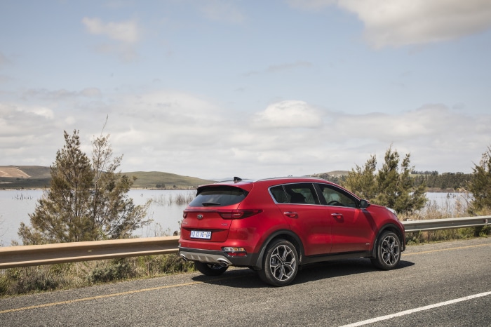 Red Kia Sportage SUV parked by a lake