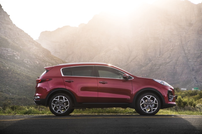 Red Kia Sportage SUV parked on a road with mountains