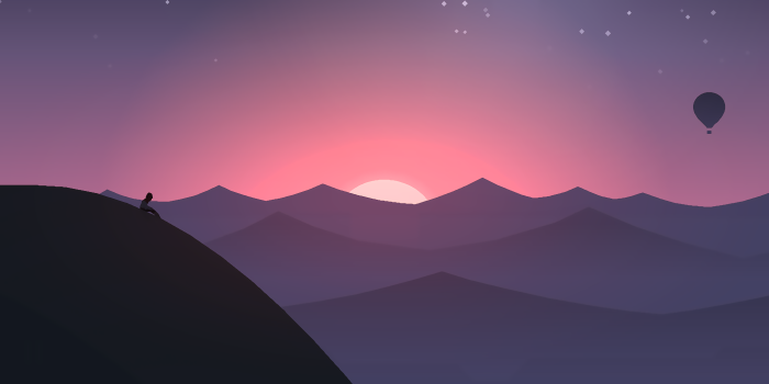 Person sitting on a hill overlooking mountains at sunset