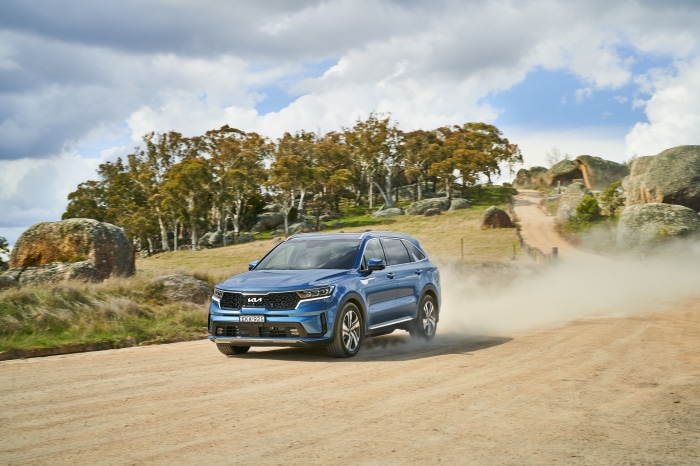 Blue Kia Sorento driving on a dirt road