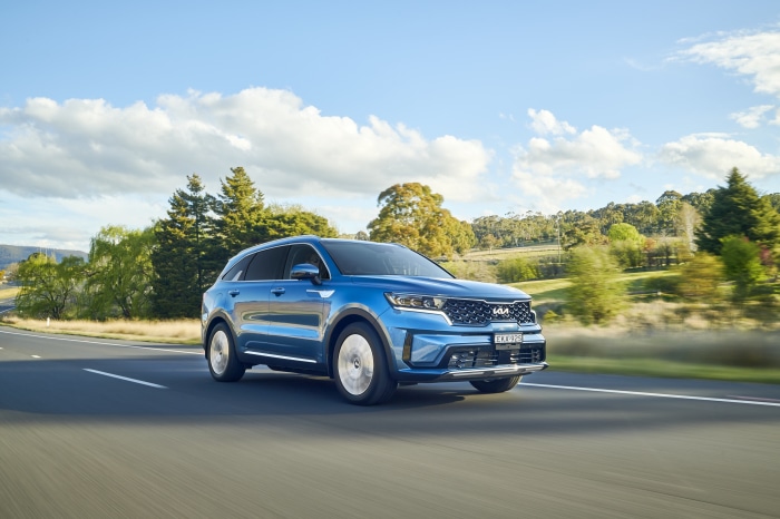 Blue Kia Sorento Plug-in Hybrid SUV driving on a road