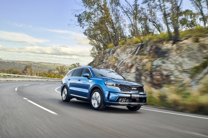 Blue Kia Sorento Plug-in Hybrid SUV driving on a road