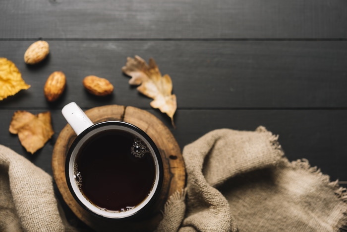 Coffee cup with autumn leaves and nuts