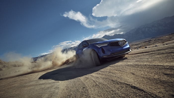 Blue Acura RDX SUV driving on a dirt road