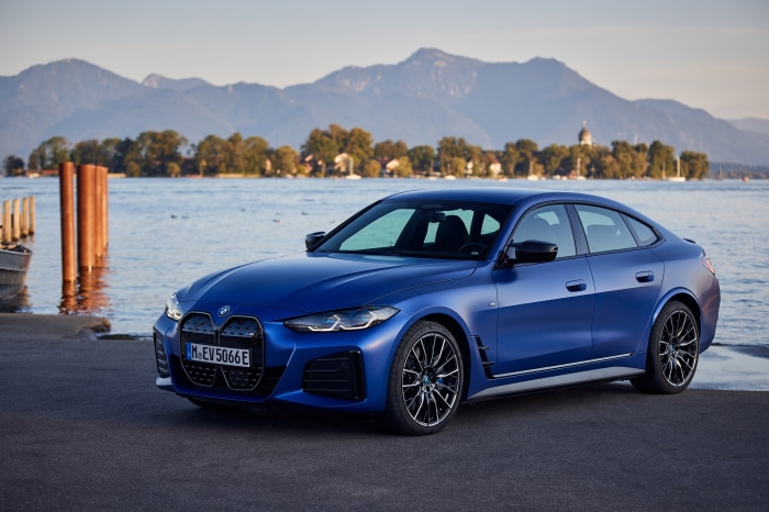 Blue BMW i4 M50 parked by a lake with mountains
