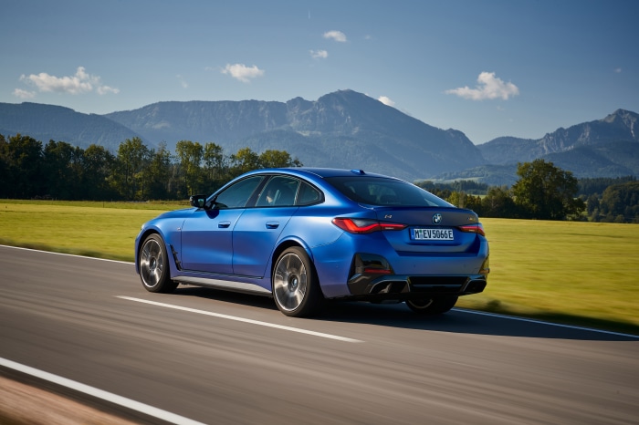 BMW i4 M50 driving on a road with mountains in the background