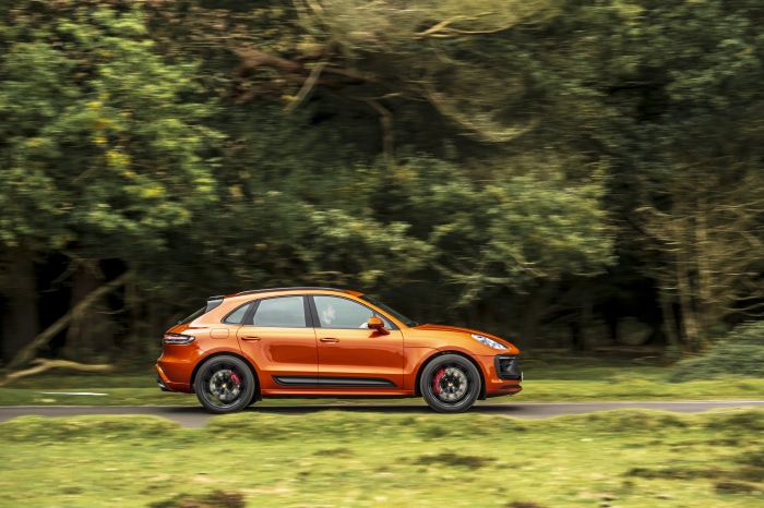 Orange Porsche Macan GTS driving on a road